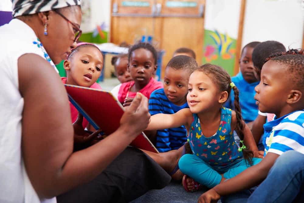 Professora lendo para um grupo com diversas crianças negras.