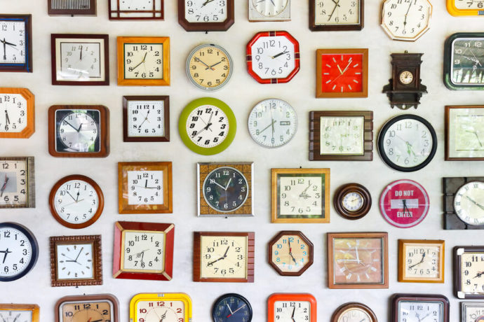 Vários relógios diferentes pendurados em uma parede.